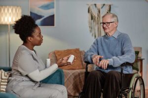 Two family members talking with an elderly resident in a cozy assisted living common area.