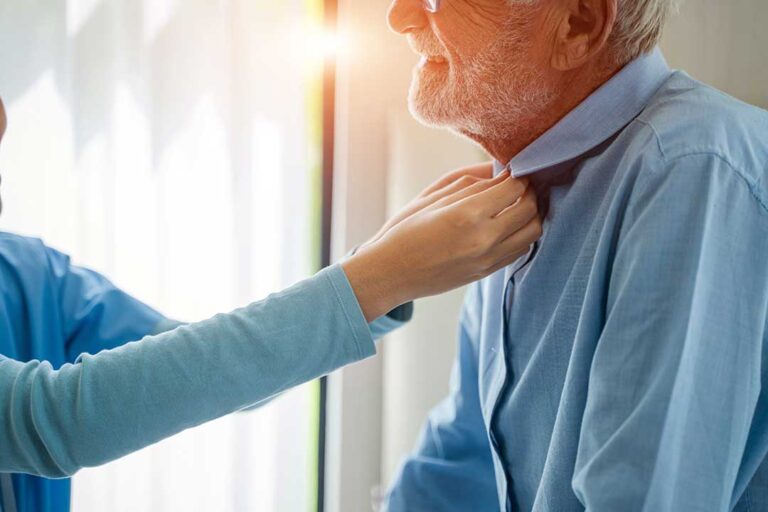 Older adult speaking with a caregiver in a bright assisted living apartment.