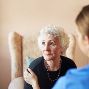 Older adult and family member reviewing care options at a table with medication lists and facility brochures.